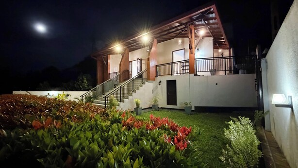Una casa de dos pisos con escaleras, un balcón y un exterior bien iluminado.
