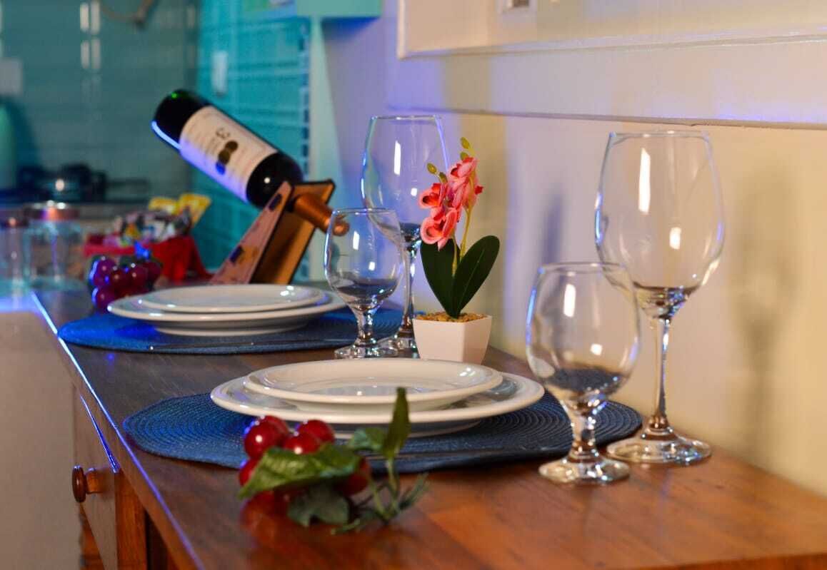 Mesa de jantar posta com pratos, copos de vinho e uma garrafa de vinho.