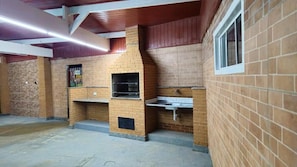 A brick interior with a built-in oven and sink, wooden ceiling beams, and a window.