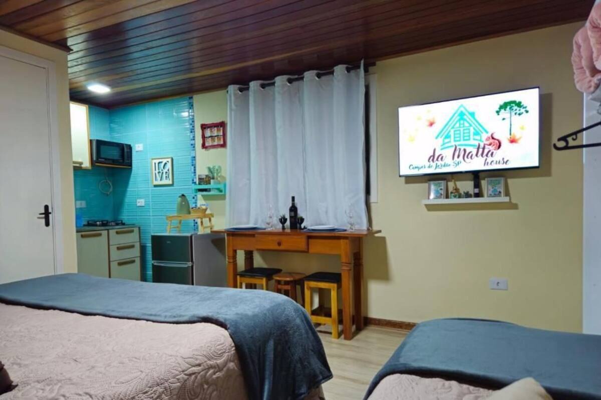 Una camera da letto con due letti, una scrivania, una televisione e un angolo cottura.