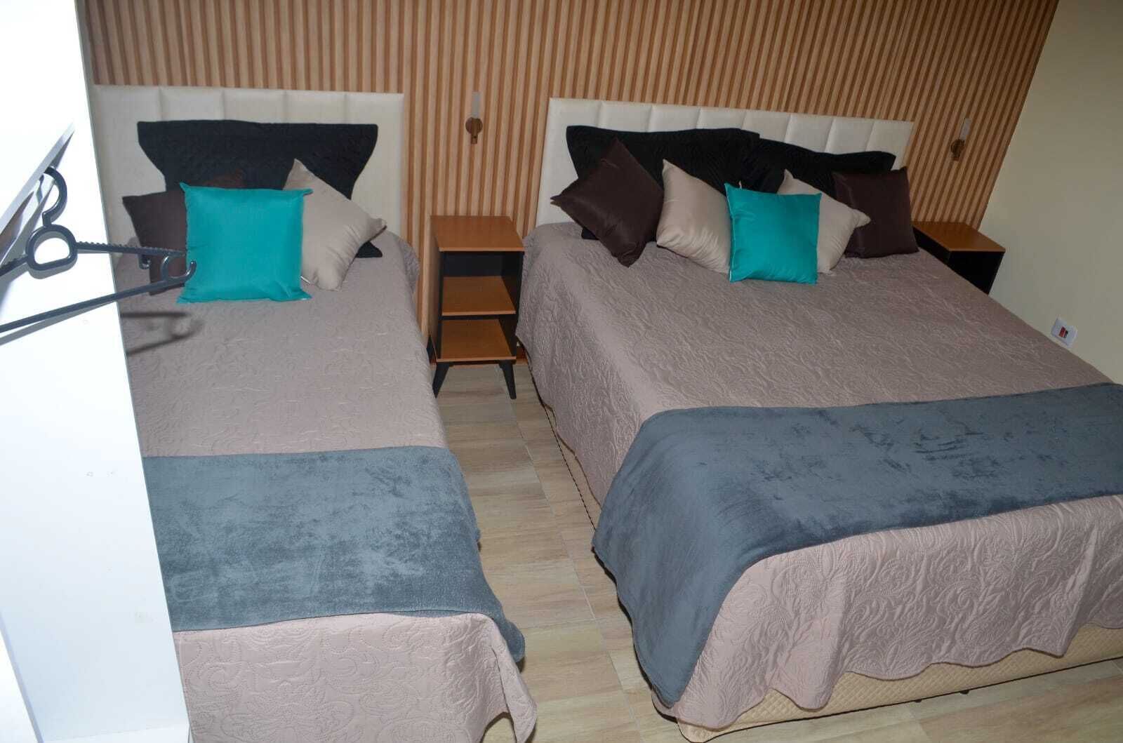A double bed room with two nightstands, each with a lamp. The room has a striped wallpaper and a wooden floor.