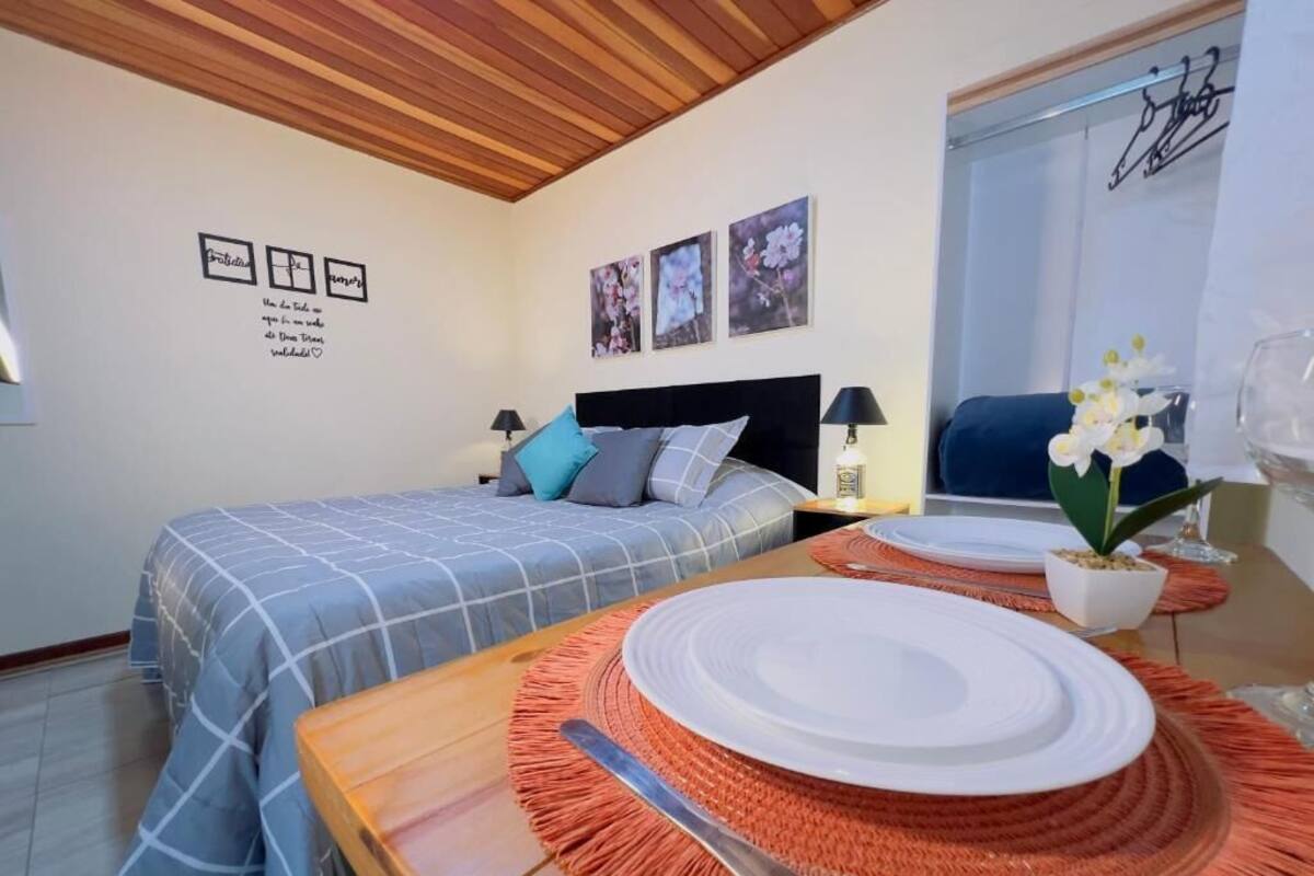 Una camera da letto con un letto, comodini, un tavolo da pranzo con un piatto e posate, e decorazioni alle pareti.