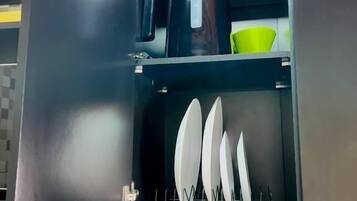 A kitchen with a microwave, a green bowl, and a rack with white plates.