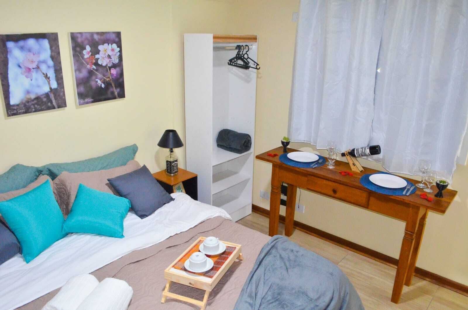 A bedroom with a bed, bedside table, and a dining table set for two.