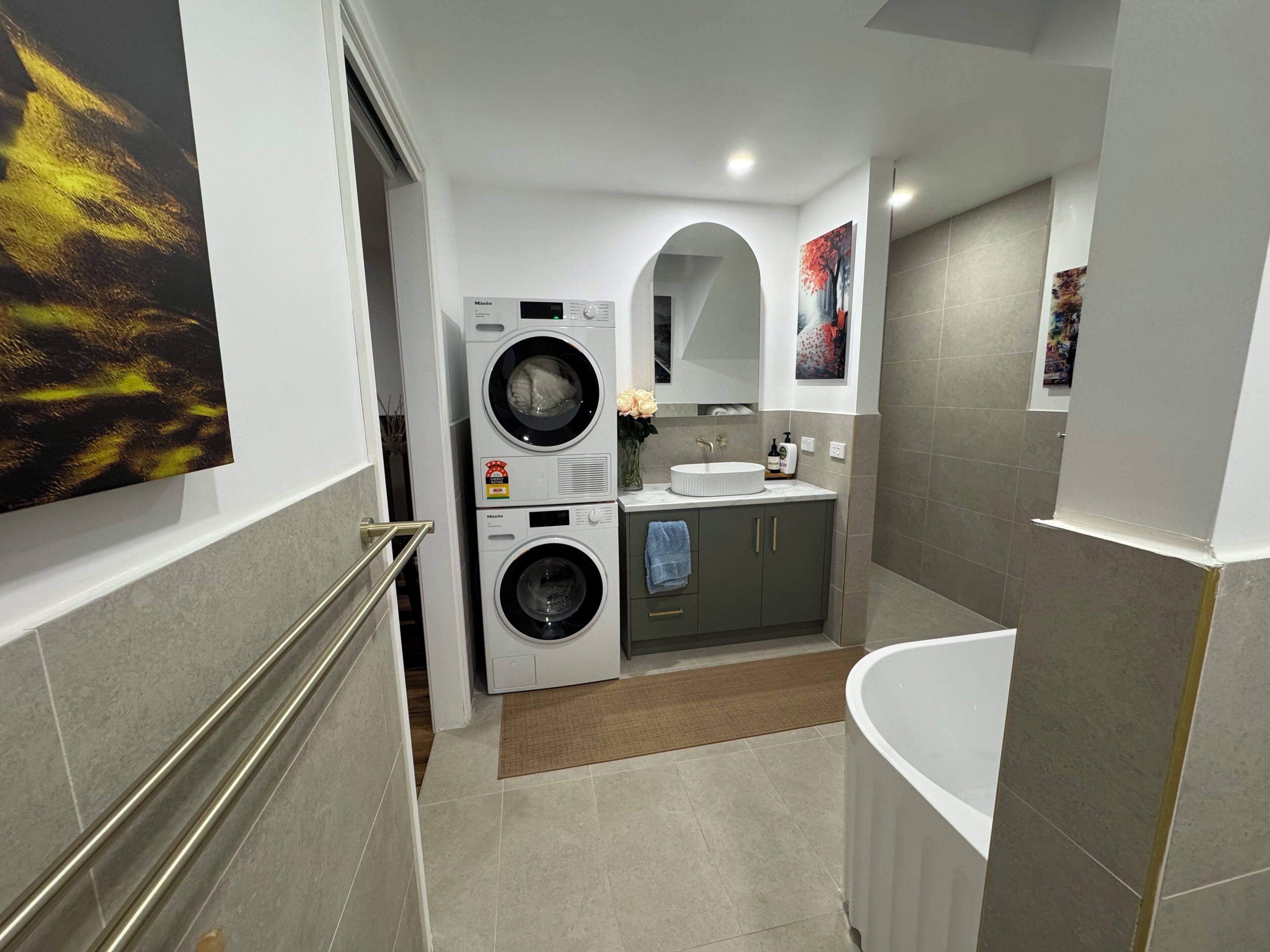 Une salle de bain moderne équipée d’un lave-linge intégré, d’un évier et d’une baignoire.