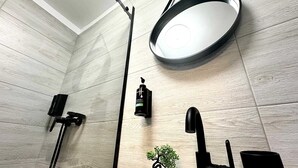A modern bathroom with a round mirror, black faucet, and a small potted plant on the sink. - 3 Baneasa Airport (Bucharest)