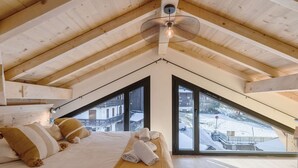 Une chambre avec un plafond en pente, de grandes fenêtres et un lit avec des serviettes.