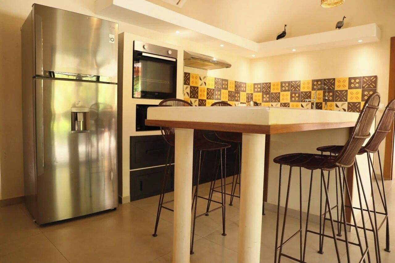 A compact kitchen with a stainless steel refrigerator, a built-in oven, and a tiled backsplash.
