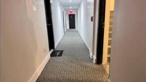 Un couloir d'hôtel avec des revêtements de sol en moquette et des portes de chaque côté.