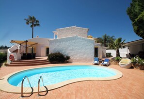A swimming pool with a white building in the background, a palm tree, and a clear blue sky. - Beachfront location - Ideal family home - Pool & garden (Armação de Pêra)
