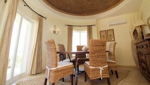 Un comedor con sillas de mimbre, una mesa de madera y un techo curvo.