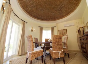 A dining area with wicker chairs, a wooden table, and a curved ceiling. - Beachfront location - Ideal family home - Pool & garden (Armação de Pêra)