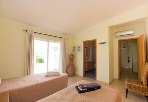 A hotel room with two beds, a large vase, and a wicker chair. - Beachfront location - Ideal family home - Pool & garden (Armação de Pêra)