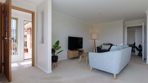 A living room with a grey sofa, a TV, a lamp, and a plant. - Steps From The Hospital in Burnie (Burnie City)