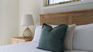A neatly made bed with striped bedding and a wooden headboard. - Steps From The Hospital in Burnie (Burnie City)