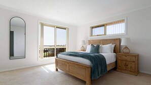 A bedroom with a large bed, two bedside tables, a nightstand, a mirror, and a window with blinds. - Steps From The Hospital in Burnie (Burnie City)
