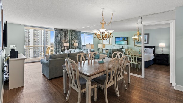 A spacious living room with a dining area, a sofa set, and a chandelier. - S Hampton 1406 3 Br Oceanview in Kingston, Pool (Myrtle Beach)