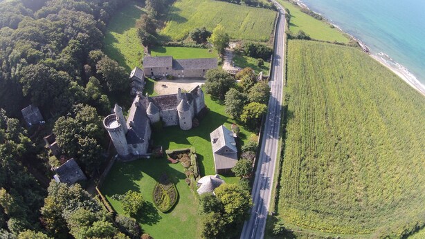Vista aérea de un castillo con una carretera costera cerca.