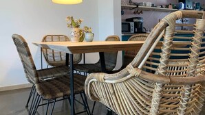 Un comedor con sillas de mimbre, una mesa de madera y lámparas colgantes.