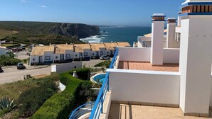 Un hotel frente al mar con piscina, vistas al océano y zona de estacionamiento.