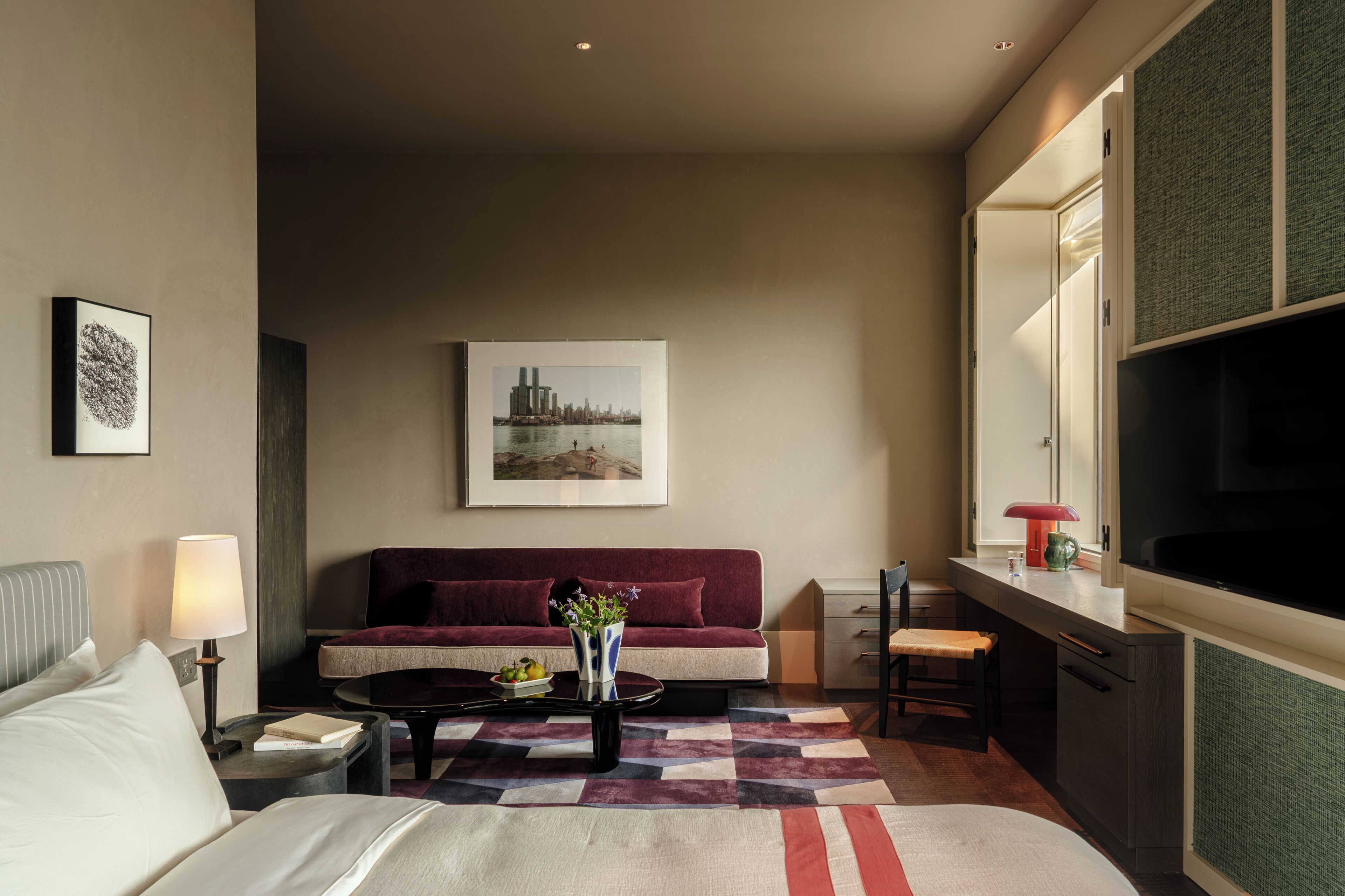 A modern hotel room with a bed, a sofa, a coffee table, and a dining area.