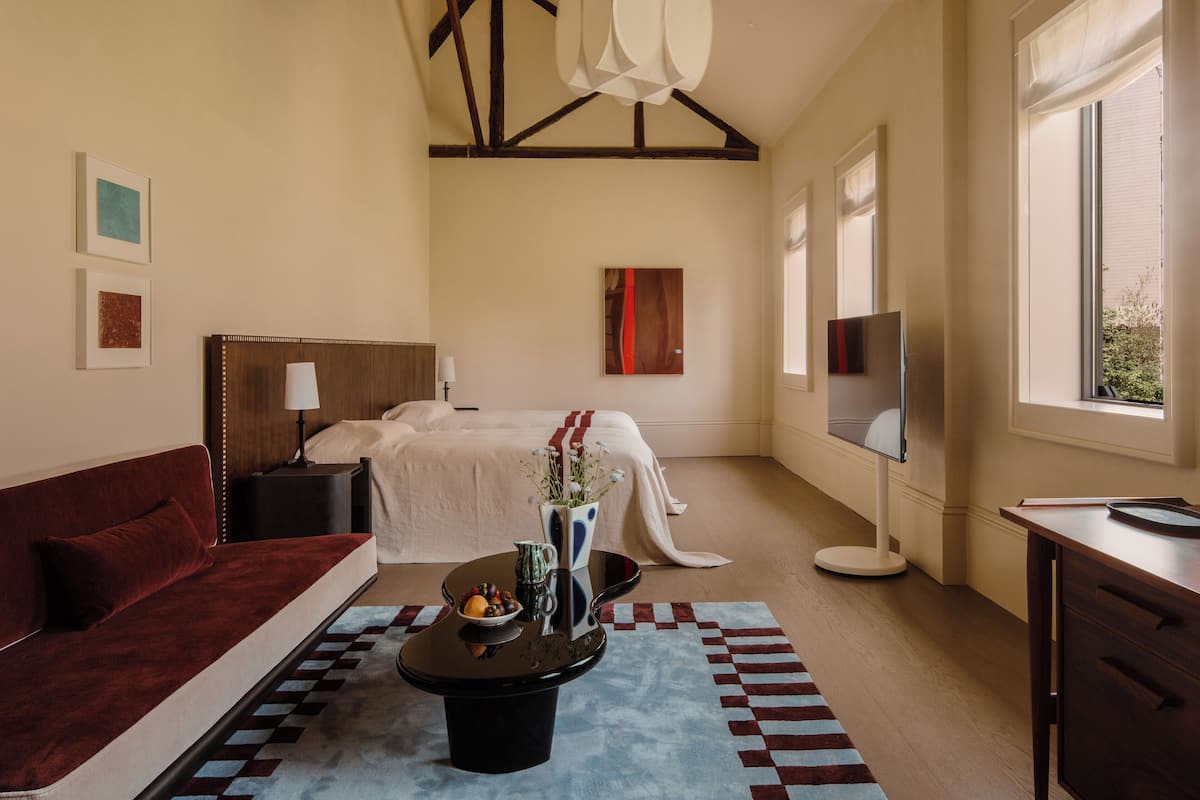 Een hotelkamer met een bed, een bank, een bijzettafeltje met fruit, een televisie en een raam met uitzicht.