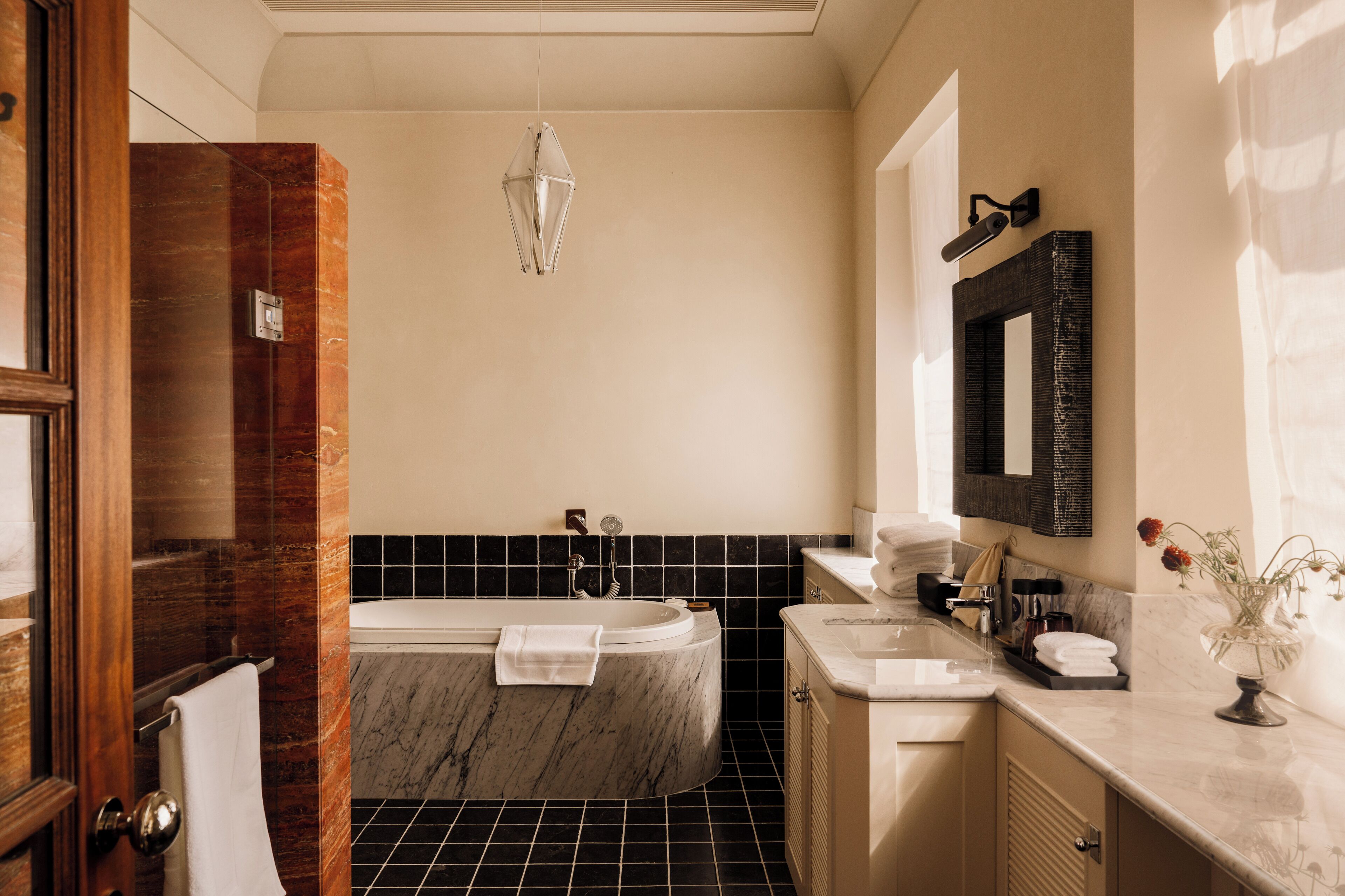 Un baño moderno con una bañera de mármol, un espejo grande y un tocador con lavabo.