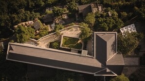 An aerial view of a building with a unique architectural design, featuring a prominent curved structure and a large central courtyard. - Sunyata Mountain Alley Chongqing Resort (Chongqing)