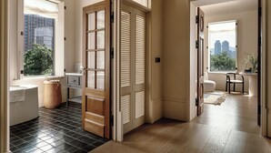 A modern interior with a large sliding door leading to a balcony, a black and white tiled floor, and a view of city buildings. - Sunyata Mountain Alley Chongqing Resort (Chongqing)