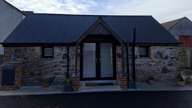 A stone building with a dark metal roof, a black door, and a small porch with potted plants. - Kintrae Cottage


Close to Game of Thrones Studio (Banbridge)