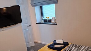 A hotel room with a bed, a TV mounted on the wall, a window with a view, and a small shelf with items. - Kintrae Cottage


Close to Game of Thrones Studio (Banbridge)