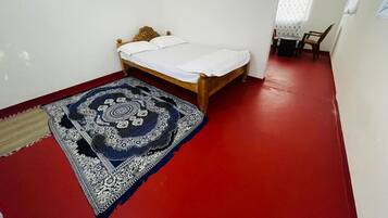 Un dormitorio con una cama de madera, suelo rojo y una alfombra estampada.