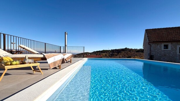 A clear blue swimming pool with lounge chairs and a stone building in the background. - Villa Billubium-Authentic Stone Villa with Private Heated Pool (Lokvičići)