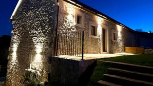 A stone building with a lit entrance and a small porch. - Villa Billubium-Authentic Stone Villa with Private Heated Pool (Lokvičići)
