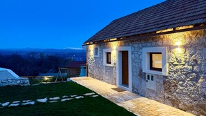 A stone house with a tiled roof, a paved entrance, and a view of distant mountains. - Villa Billubium-Authentic Stone Villa with Private Heated Pool (Lokvičići)