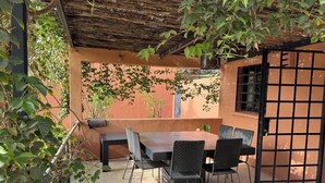 An outdoor patio with a table and chairs, surrounded by plants and a pergola. - Villa SOPHIA (Ngaparou)
