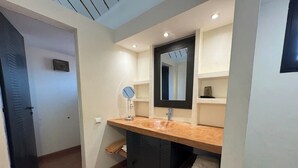 A compact bathroom with a wooden vanity, a mirror, and a towel rack. - Villa SOPHIA (Ngaparou)