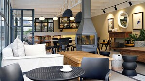 Un espacio interior con mesas y sillas, una chimenea y una zona de bar con estantes llenos de botellas.