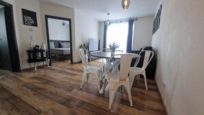 A modern living room with a dining area, wooden flooring, and a large mirror on the wall. - Modern 2-room vacation apartment with balcony and space for up to 4 guests (Bremen)