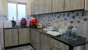 A kitchen with wooden cabinets, a tiled backsplash, and various kitchen appliances. - Ideal Holiday Destination for Families (Murree)