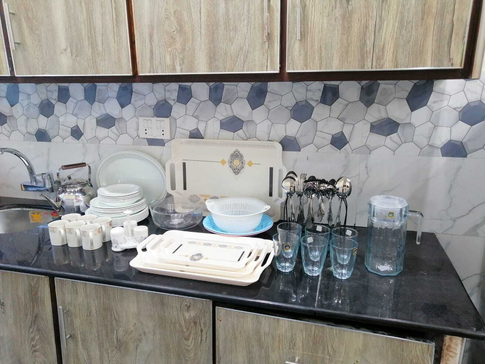 A kitchen with a tiled backsplash, a sink, and various dishes and utensils.