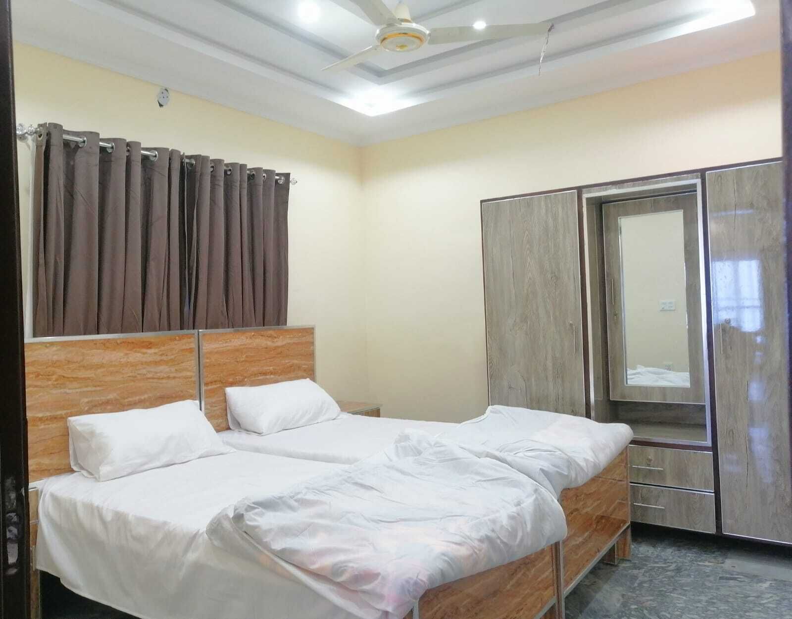 A hotel room with two beds, a wardrobe, and a mirror.