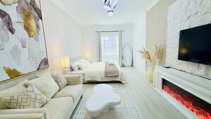 Ein modernes Hotelzimmer mit Bett, einer Couch, einem Flachbildfernseher und einem Kamin.