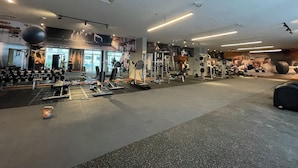 Ein Fitnessstudio mit unterschiedlichen Trainingsgeräten, darunter Gewichte, Laufbänder und eine große Trainingskugel.