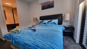 Une chambre d’hôtel avec un lit, une table de chevet, une lampe et un tableau au mur.