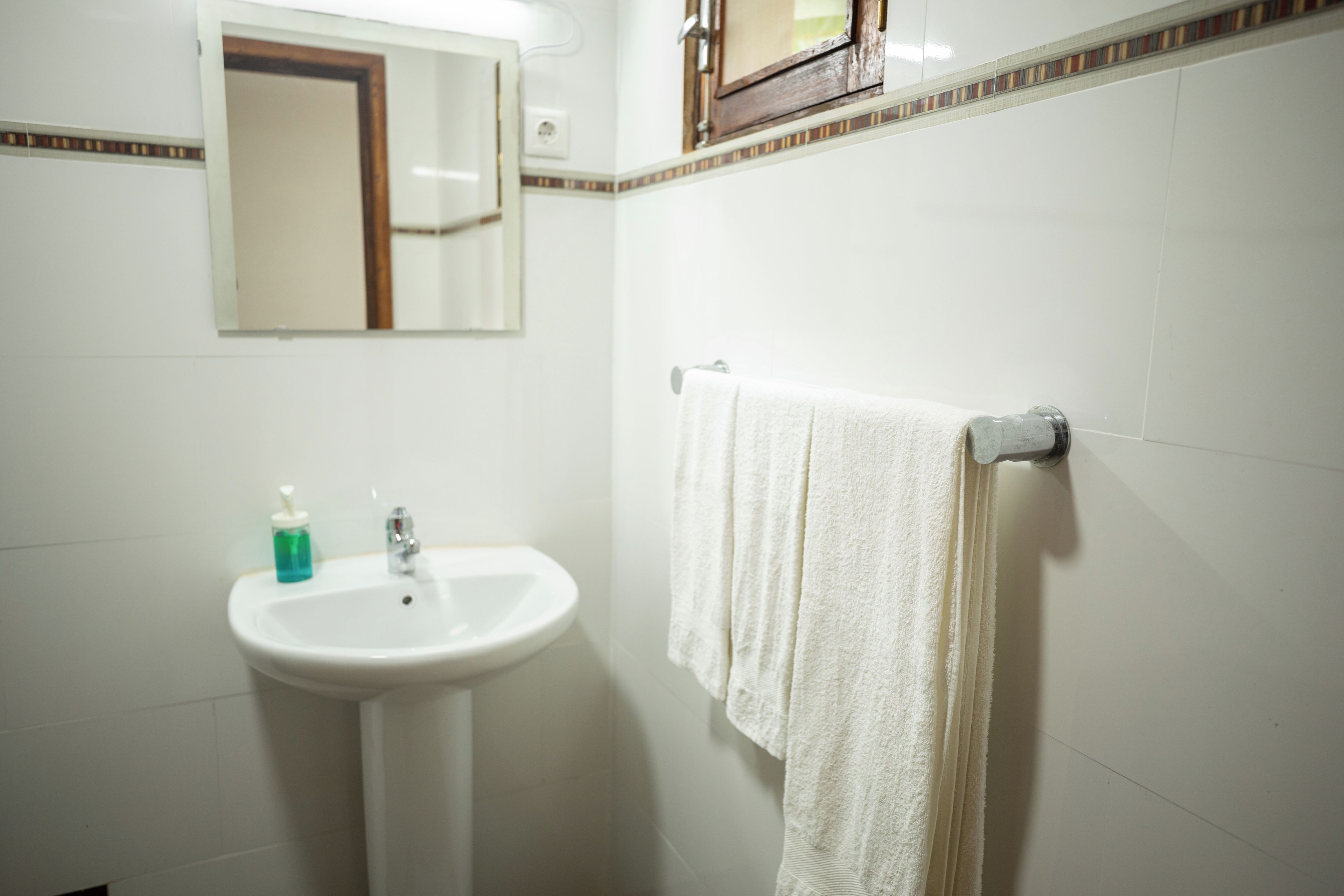 A bathroom with a white sink, a mirror, and a towel rack.