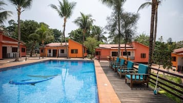 Una piscina con sillas de descanso y palmeras.