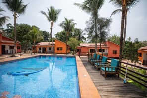 Uma piscina com espreguiçadeiras e palmeiras.