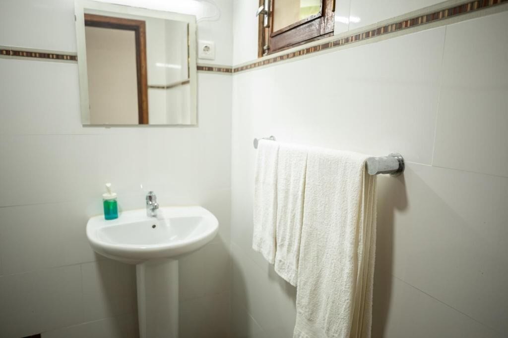 A bathroom with a white sink, a mirror, and a towel rack.
