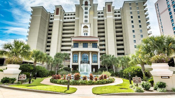 A large hotel with a central fountain, multiple balconies, and lush landscaping. - Southwind 204 1 Bedroom Condo (Myrtle Beach)